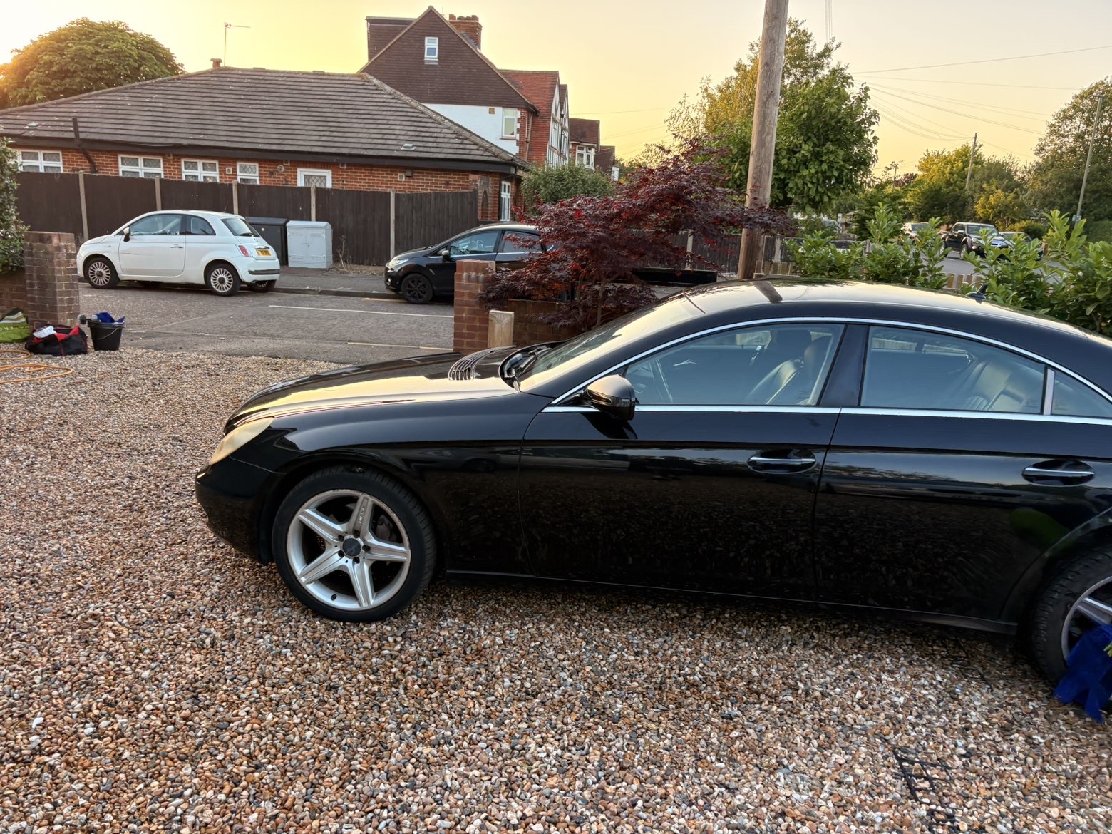Black Mercedes CLS washed to a mirror gloss on a driveway at golden hour